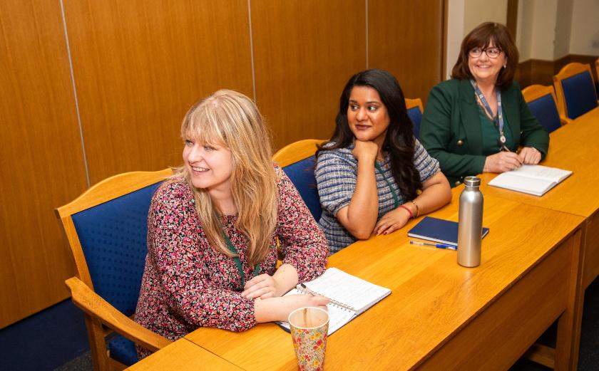 Three people sat at a desk looking at a presentation